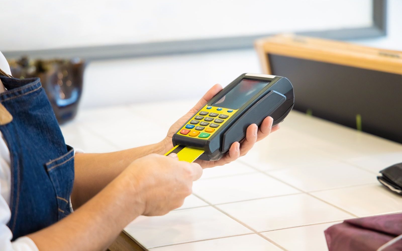 A merchant holding a card payment terminal in her shop