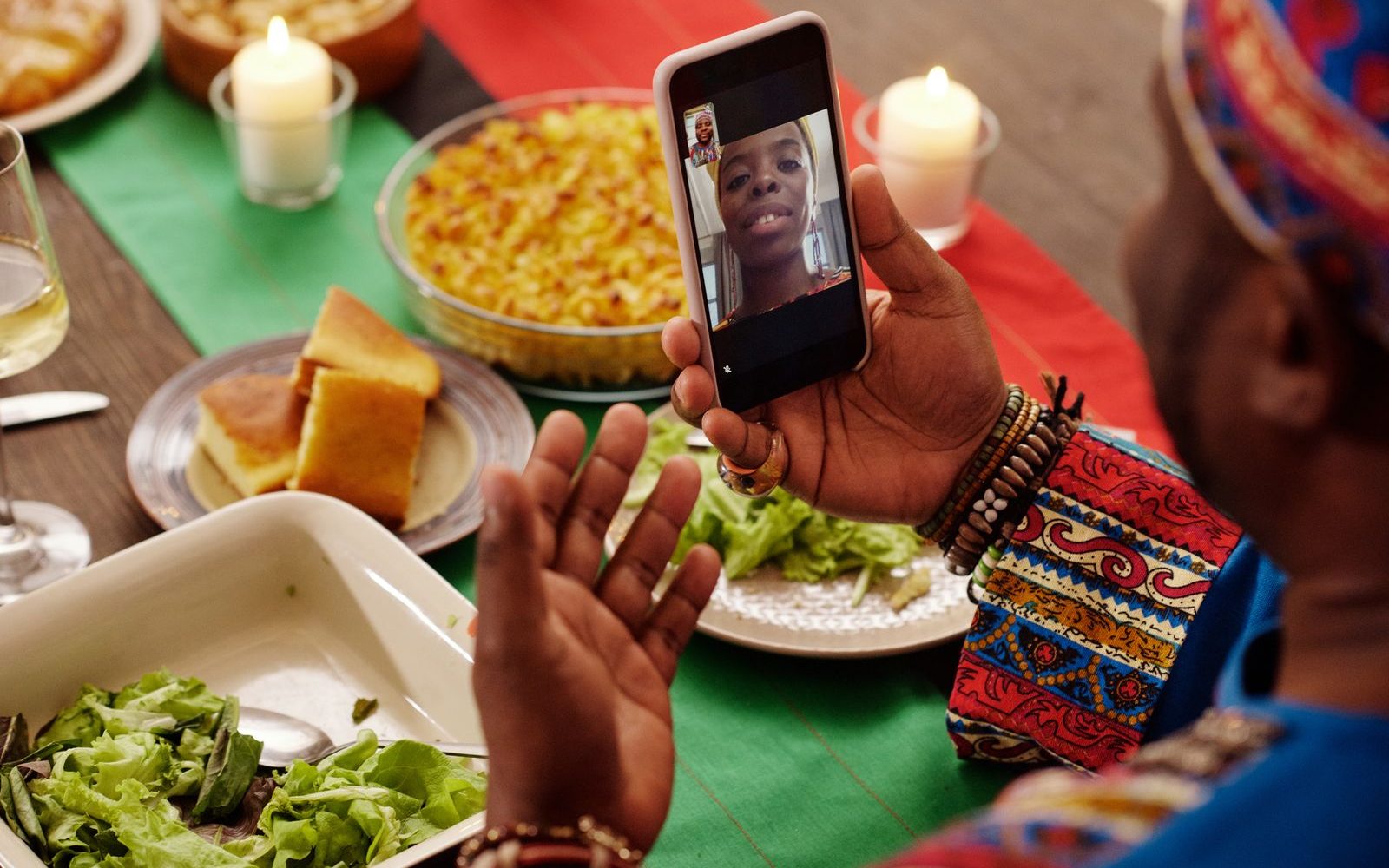 A family sharing a video call on a phone around the dinner table