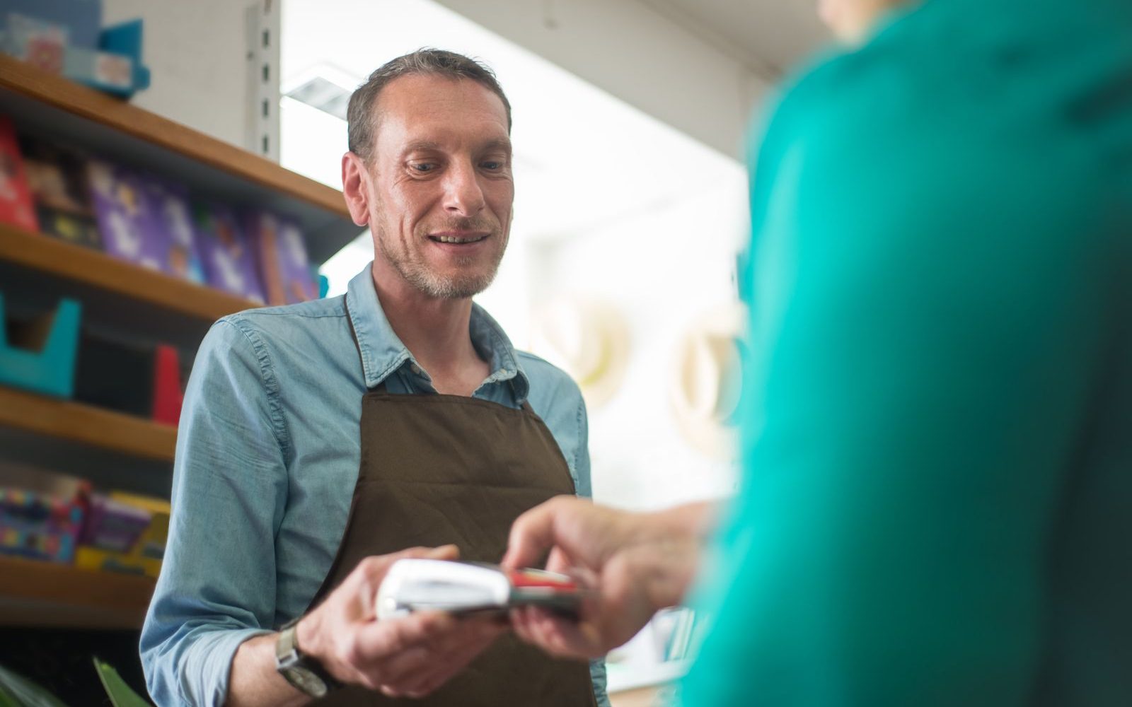 A shop owner handing a card terminal to a customer