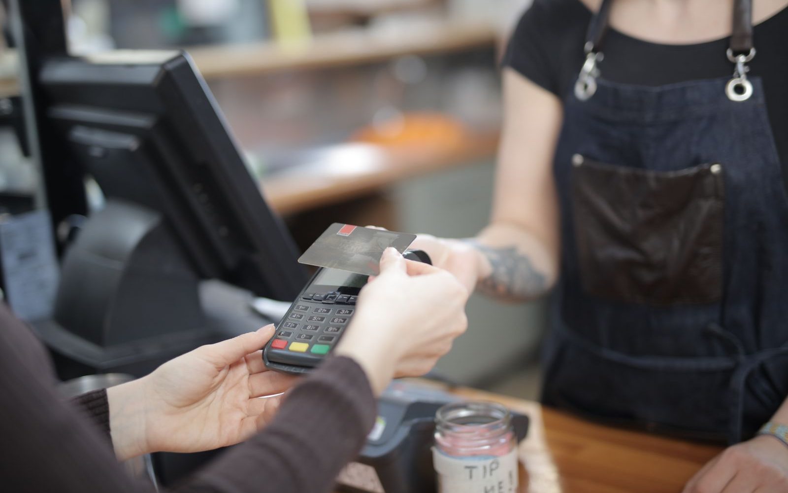 A customer paying by card on a terminal at a shop counter